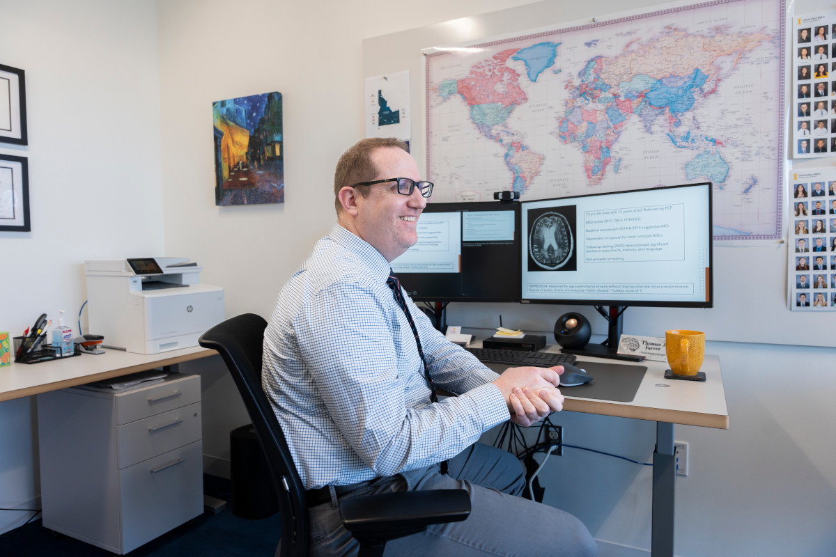 Researcher sits at desk and shows brain scan research.